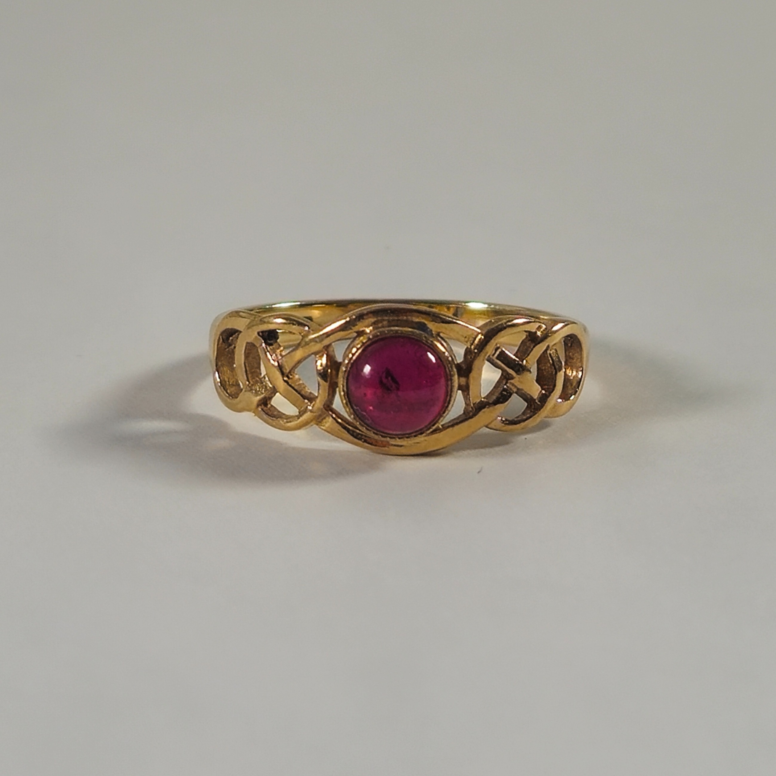 Product photo for 9ct Gold Round Cabochon Purplish Red Stone Celtic Shoulder Ring Size N